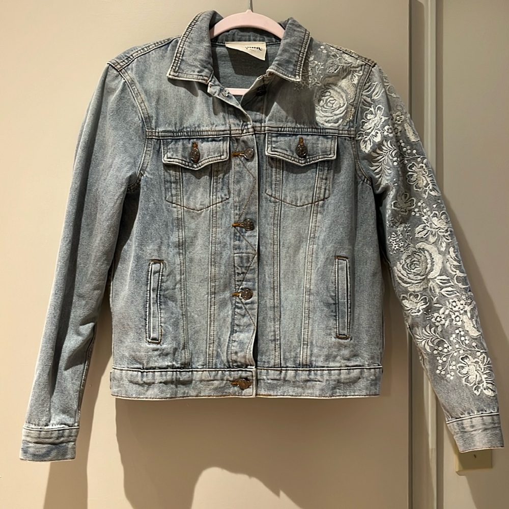 Light wash denim jacket with embroidered sleeve.